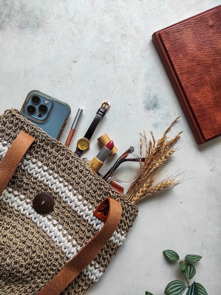 purse with phone and items sticking out. leather journal. white background.