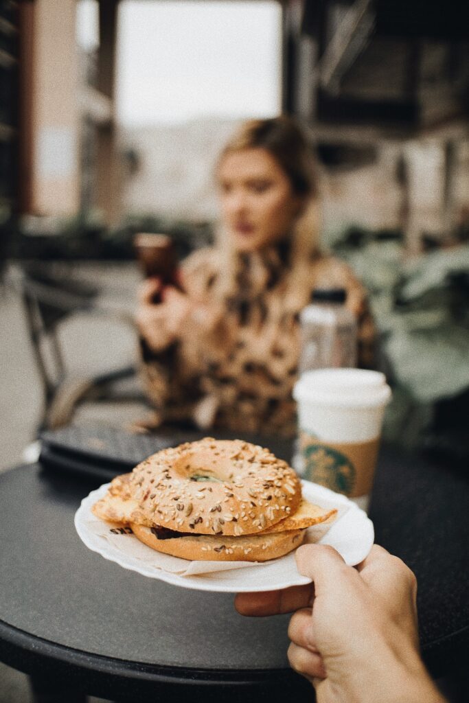 bagle on plate being carried to a woman in the background. cafe. blurry background.