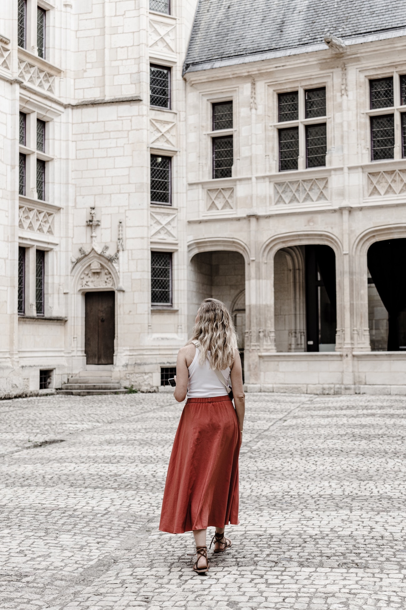 woman in a courtyard. all concrete. pretty stone house.