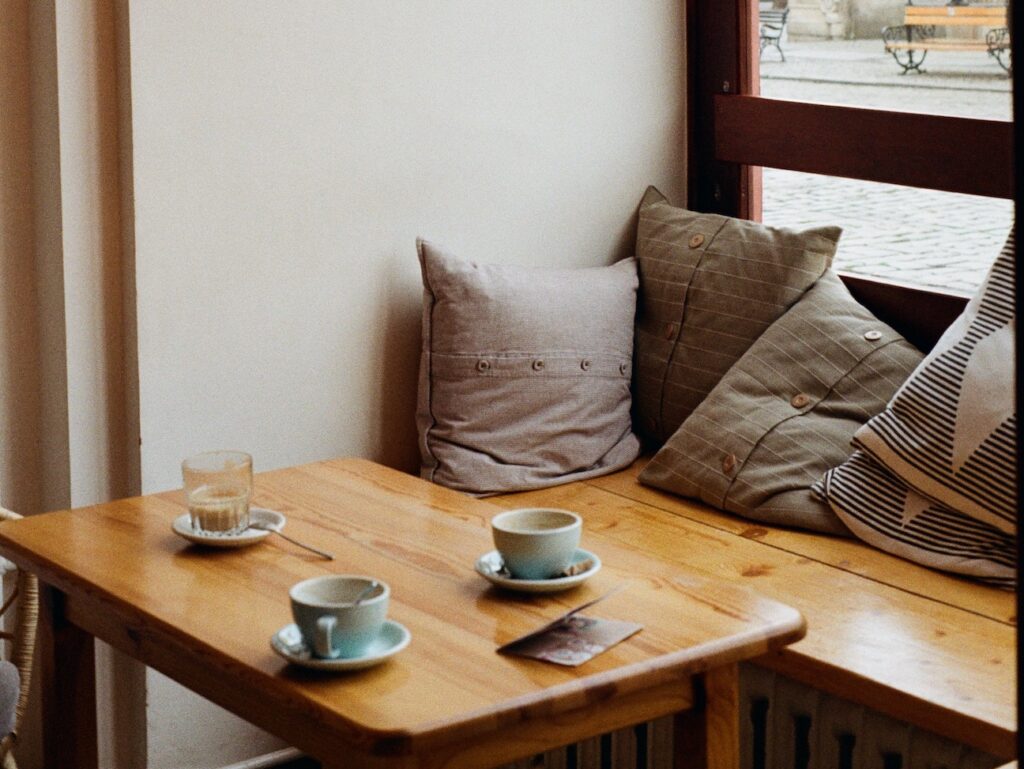 table with coffde cups in front of a window with a cute hanging lamp light and poster in background