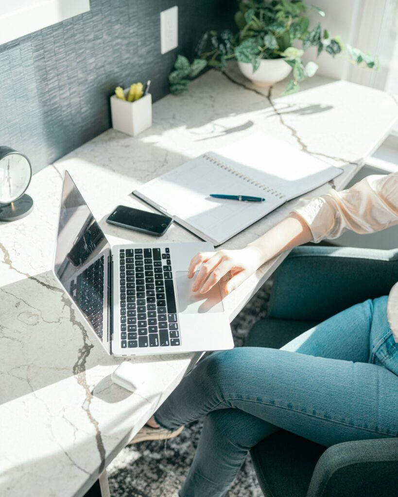 laptop on desk with woman at it. no face showing.